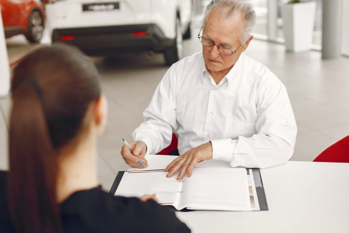 old man sitting car salon talking with manager