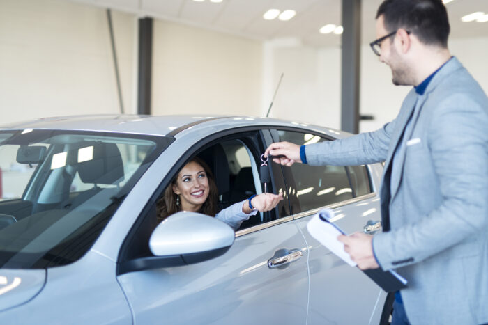 vehicle dealer handing keys new car owner