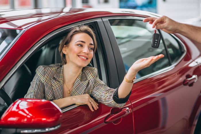 Noleggio auto usate senza anticipo: come funziona e a chi conviene woman sitting red car receiving keys