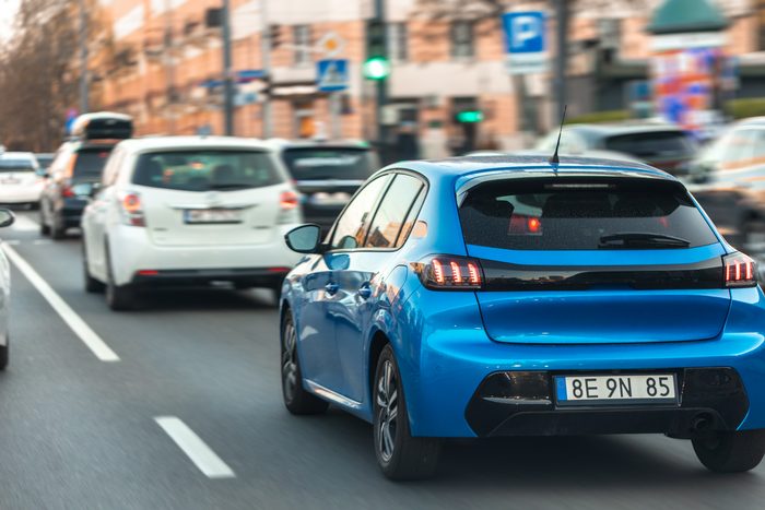 blue hatchback driving city street modern car heavy urban traffic city center