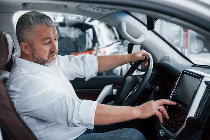 everything working perfectly senior businessman official clothes sits luxury car pushing buttons music player