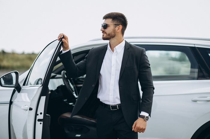 handsome business man by white car