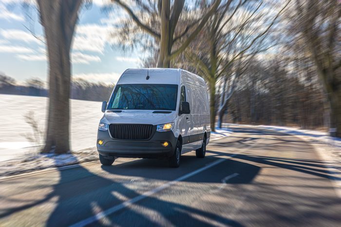 white delivery van driving winter road near snowy field commercial transport concept